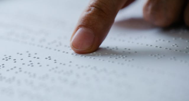 doigt parcourant un livre en braille
